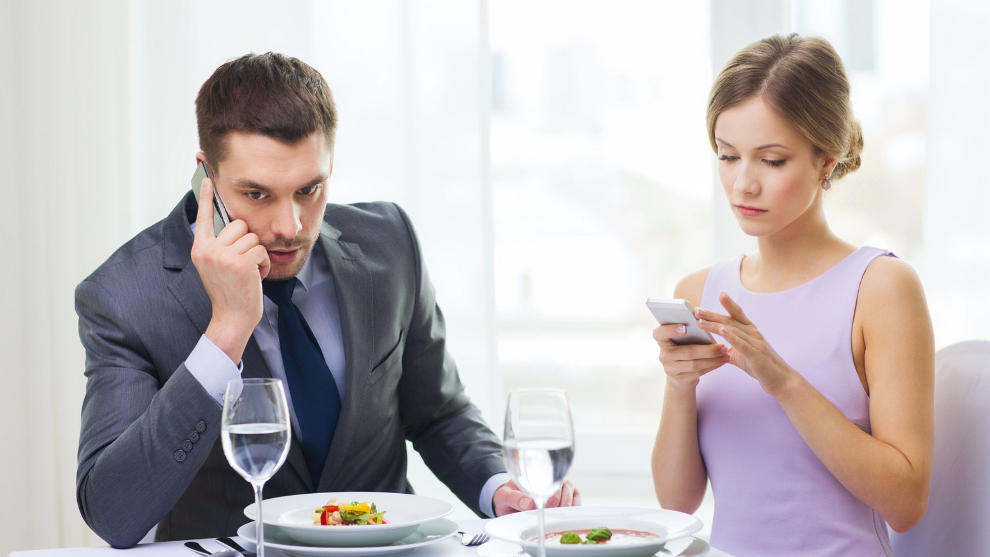 A couple using phones showcasing dining experience & restaurant etiquette's importance
