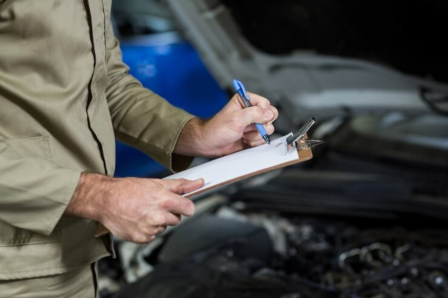An official noting down the illegal car modifications durin a MOT test